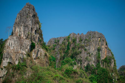 Low angle view of rock formation against clear blue sky