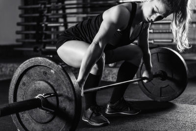 Cross training. female athlete lifting heavy barbells