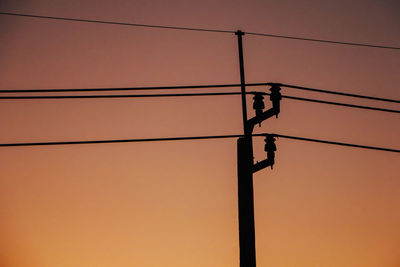 Low angle view of silhouette electricity pylon against sky during sunset