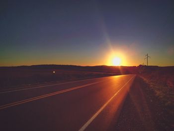 Empty country road against clear sky at sunset