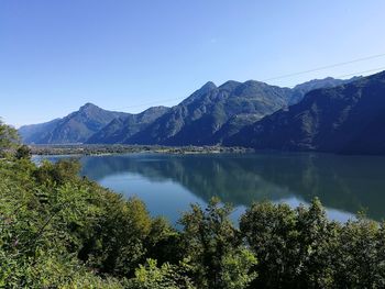 Scenic view of lake and mountains against clear blue sky