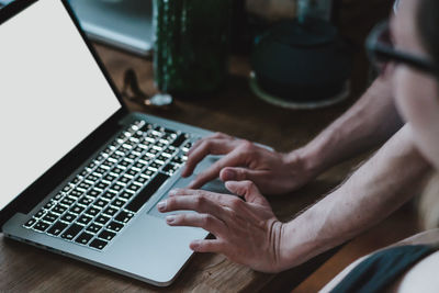 Close-up of hand using laptop on table