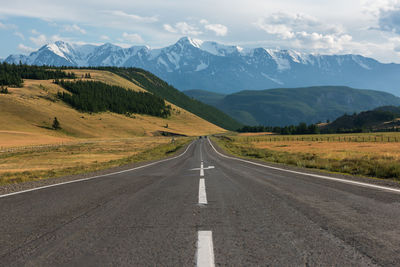 Road leading towards mountains against sky