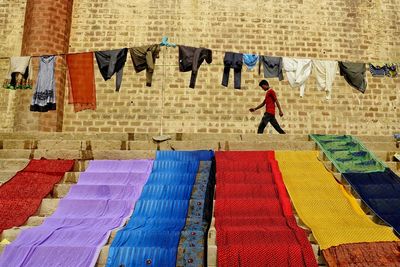Man walking by colorful clothes against wall on sunny day