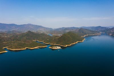 Aerial view of lake and mountains against blue sky