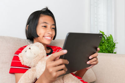 Portrait of smiling woman holding mobile phone at home