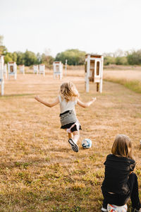 Girl playing soccer while running on grass at park