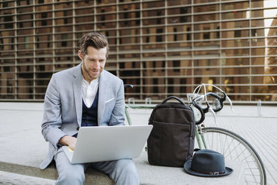 Male professional working on laptop while sitting on bench
