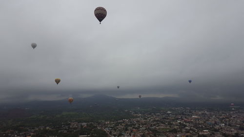 Hot air balloons flying in city against sky