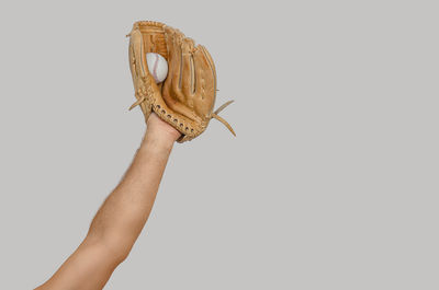 Cropped hand of person holding key against white background