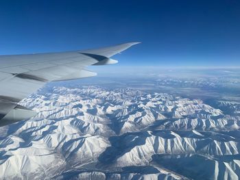 Aerial view of snowcapped mountain against blue sky