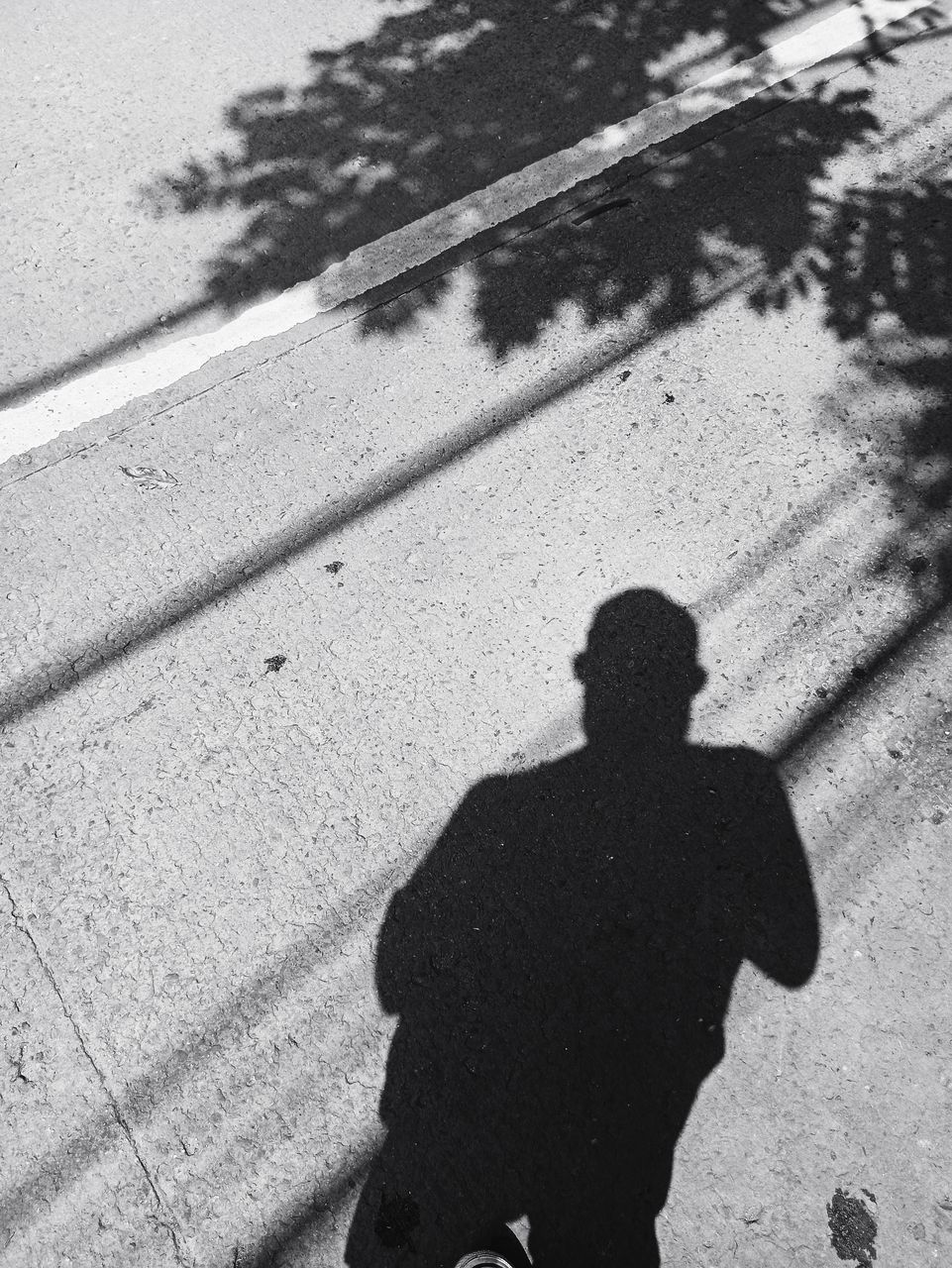 shadow, high angle view, black, sunlight, black and white, men, lifestyles, day, one person, focus on shadow, city, monochrome, nature, street, monochrome photography, leisure activity, white, footpath, standing, outdoors, adult, road, silhouette, walking