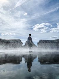 Digital composite image of man standing by lake against sky
