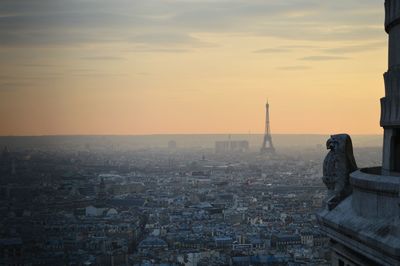 Distant view of eiffel tower amidst buildings against sky during sunset in city