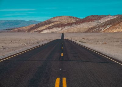 Road leading towards mountains against sky