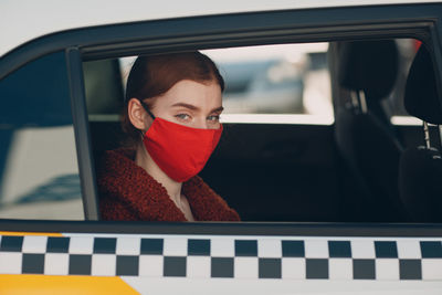 Portrait of woman wearing mask sitting on taxi