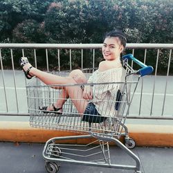 Portrait of woman sitting in shopping cart