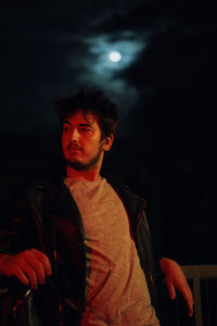 Portrait of young man looking away at night