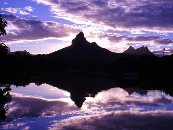 Reflection of silhouette mountains on lake during sunset