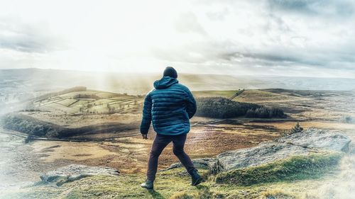 Rear view of man standing on shore against sky