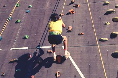 Low angle view of girl climbing on artificial wall