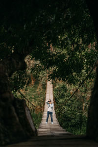 Man photographing while standing on rope bridge