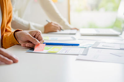 Midsection of woman holding paper with text on table