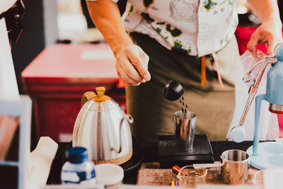 Barista weighting coffee beans on digital scale.