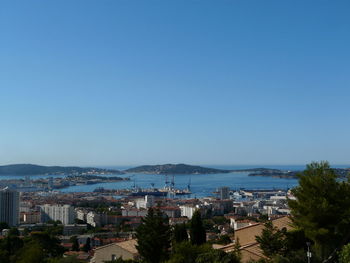 High angle view of city by sea against clear blue sky