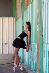 Side view of woman standing against wall