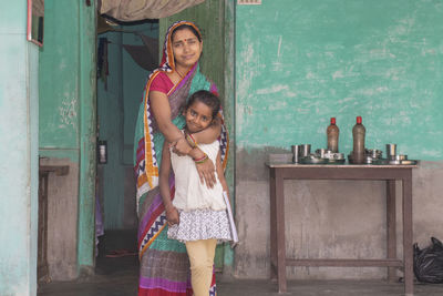 Portrait of happy mother and daughter standing at door of the house in rural india