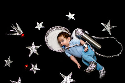 Digital composite image of boy playing with balloons against black background