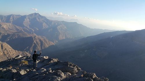 Hiker standing on mountain against sky during foggy weather