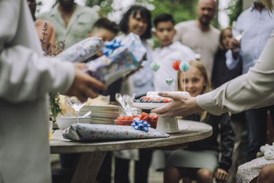 Hands of woman keeping decorated birthday cake on table