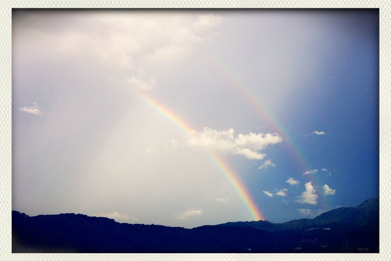 sky, scenics, transfer print, rainbow, beauty in nature, tranquil scene, tranquility, cloud - sky, mountain, auto post production filter, nature, landscape, multi colored, idyllic, cloud, outdoors, no people, blue, cloudy, weather