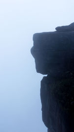 Rock formations by sea against clear sky