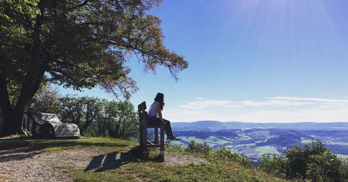 Woman sitting on chair against blue sky