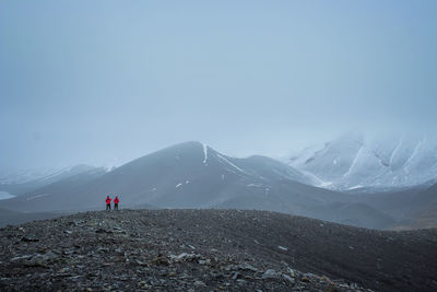 People on snowcapped mountain against sky