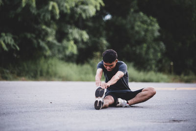 Man sitting on road in city