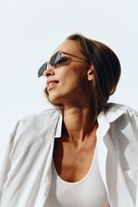 Young woman wearing sunglasses against white background