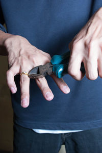 Midsection of man removing wedding ring with hand tool