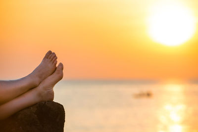 Midsection of person against orange sky during sunset