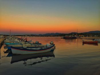 Boats moored in calm lake at sunset