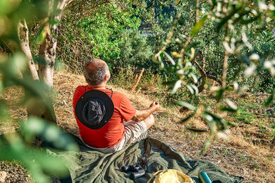 Tourist man resting in olive grove, meditating in front of mountain view or exercising outdoors. 