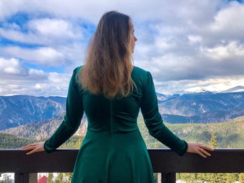 Rear view of woman standing in balcony against mountains