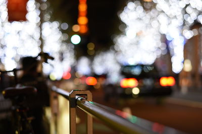 Close-up of illuminated railing in city at night