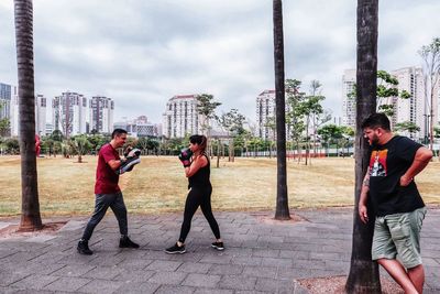 Men standing on people in city against sky