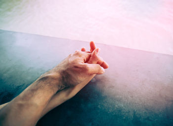 Cropped image of couple holding hands by swimming pool