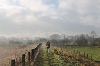 Rear view of woman walking on field