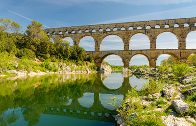 Arch bridge over river against sky